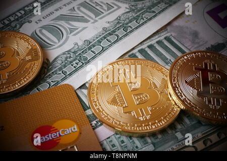 BERLIN, DEUTSCHLAND - Dezember 1, 2018: Bitcoins, eine virtuelle Währung in körperlicher Form, auf US-Dollar Noten und eine MasterCard Kreditkarte Stockfoto