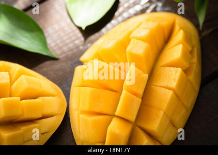 Frische reife Mangofrucht in Würfel schneiden auf hölzernen Tisch Hintergrund. Detailansicht. Gesunde vegetarische tropische Früchte Stockfoto
