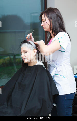 Haarpflege, Entspannung und Hairstyling Konzept. Frau sitzt im schwarzen Cape erhalten ihr Haar von Lady Friseur im Beauty Salon farbige Stockfoto