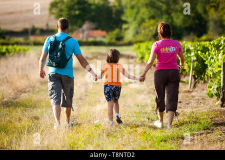 Familie einen Spaziergang durch die Weinberge in Vallet. Paare, Eltern mit ihrem Kind zu Fuß auf den Weg in die Landschaft Stockfoto