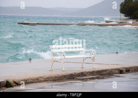 Leeren Bank durch die stürmische See von der Welle in Dalmatien Stadt am Meer in der Nebensaison bei starkem Südwind mit Regen spritzte Stockfoto