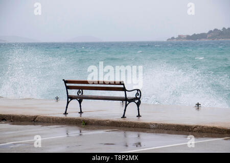 Leeren Bank durch die stürmische See von der Welle in Dalmatien Stadt am Meer in der Nebensaison bei starkem Südwind wih Regen spritzte Stockfoto