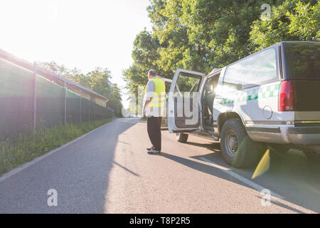 Ein reifer Mann, der neben seinem Pickup truck in sonniger Umgebung im Freien. Stockfoto