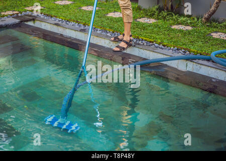 Sauberer Pool. Mann in ein blaues T-Shirt mit Reinigungsmittel für Schwimmbäder. Pool Reinigung Dienstleistungen Stockfoto