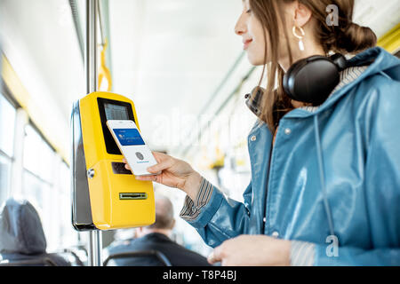 Frau Zahlung conctactless mit Smartphone für die öffentlichen Verkehrsmittel in der Straßenbahn Stockfoto