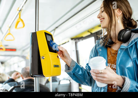 Frau Zahlung conctactless mit Bank Card für die öffentlichen Verkehrsmittel in der Straßenbahn Stockfoto