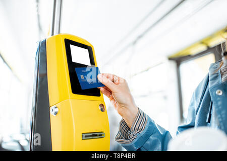 Frau Zahlung conctactless mit Bank Card für die öffentlichen Verkehrsmittel in der Straßenbahn Stockfoto