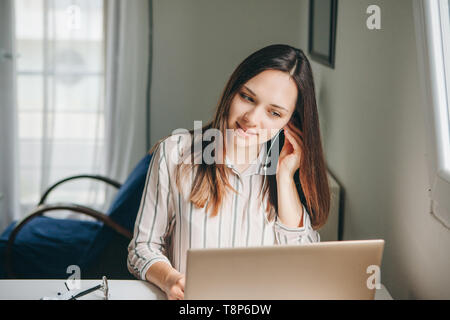 Mädchen in Kopfhörer arbeitet am Laptop im Home Office und hört Musik oder einen Podcast. Stockfoto