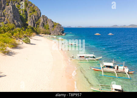 Luftaufnahme Insel mit tropischen Sandstrand und Palmen. Malajon Island, Philippinen, Palawan. touristischen Boote an der Küste tropischen Insel. Sommer und Reisen Urlaub. Strand und blaues Meer Wasser Stockfoto