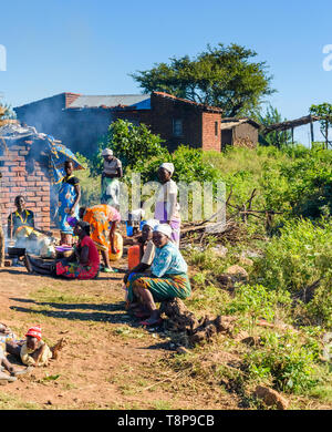 Malawische Frauen auf dem Boden wie andere Frauen kochen am offenen Feuer in Nsanje, Malawi sitzen Stockfoto