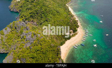 Tropischen weißen Sandstrand. Insel mit einer blauen Lagune. Boote und Menschen an der Küste der tropischen Insel. Ferienhäuser an einem tropischen Strand, Ansicht von oben Luftbild Stockfoto