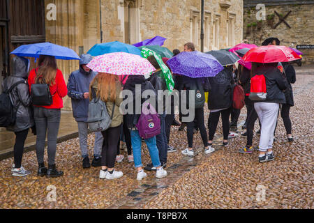 Eine Gruppe von Schülerinnen und Schülern mit Sonnenschirmen im Regen in Oxford Stockfoto