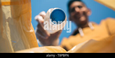 Junger Mann werfen Plastikflaschen in den Papierkorb. Stockfoto