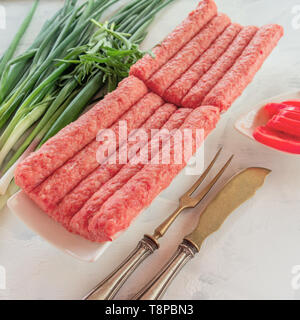 Chevapchichi ist eine nationale Balkan Teller. Nahaufnahme einer Reihe von frischem rohem Rindfleisch Kebabs Stockfoto