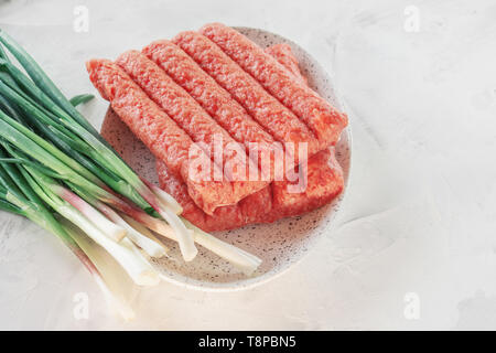 Chevapchichi ist eine nationale Balkan Teller. Nahaufnahme einer Reihe von frischem rohem Rindfleisch Kebabs Stockfoto