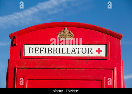 Eine leuchtend rote, traditionelle öffentliche Telefonbox, die in Peppard Common, Oxfordshire, zum Haus eines Notfall-Defibrillators in der Gemeinde umgebaut wurde Stockfoto