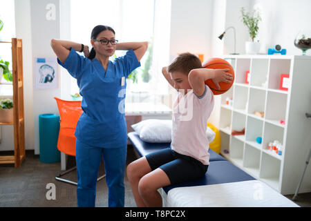 Schweren asiatischen Arzt in der blauen Uniform Prüfung Zustand ihrer Patienten Stockfoto