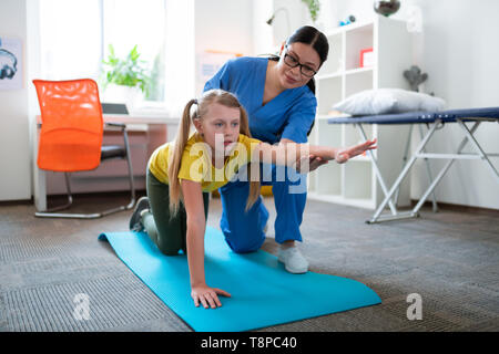 Junge Frau mit blauen Augen und gelben T-Shirt ihre Hand heben Stockfoto