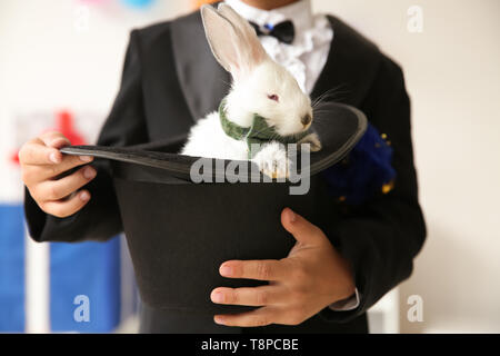 Süße kleine Magier Holding hat mit Kaninchen in Innenräumen, Nahaufnahme Stockfoto