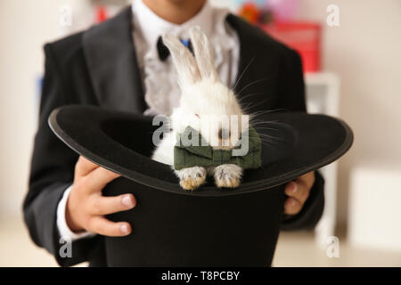 Süße kleine Magier Holding hat mit Kaninchen in Innenräumen, Nahaufnahme Stockfoto