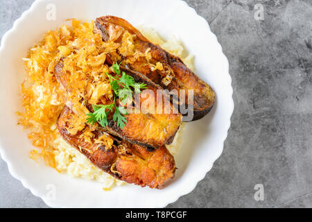 Frittierte scheiben Pangasius Fisch mit Knoblauch, mit braunem Reis serviert. Stockfoto