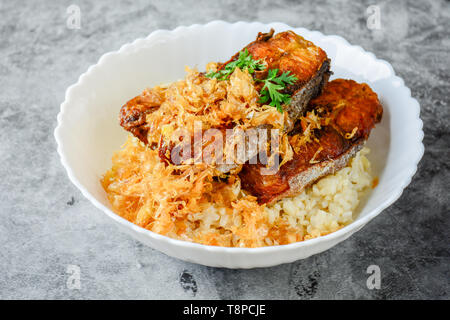 Frittierte scheiben Pangasius Fisch mit Knoblauch, mit braunem Reis serviert. Stockfoto