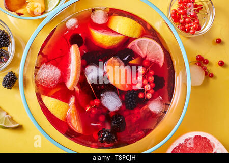 Ansicht von oben auf der Glaskanne mit hausgemachtem Frucht berry Drink mit Eiswürfeln auf gelbem Hintergrund Stockfoto