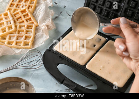 Frau gießen Rohteig in modernen Waffeleisen, Nahaufnahme Stockfoto