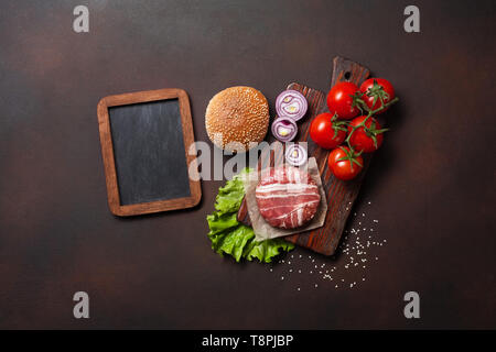 Hamburger Zutaten roh Schnitzel, Tomaten, Salat, Brötchen, Käse, Gurken und Zwiebeln auf Rusty Hintergrund. Ansicht von oben mit Platz für Ihren Text. Stockfoto