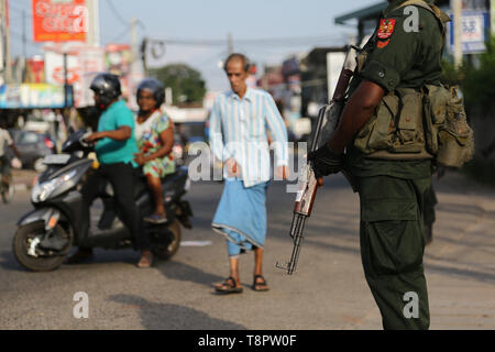 Minuwangoda, Sri Lanka. 14 Mai, 2019. Eine Sri Lankan Sicherheit Personal steht in der Nähe von einem beschädigten Shop nach einem Mob Angriff in Minuwangoda am 14. Mai 2019. Mob Angriffe auf muslimische Gemeinschaften in Sri Lanka's toter Links haben und dutzende von Geschäften und Moscheen zerstört, wie kommunale Gewalt im Zuge von Ostern Bombenanschläge, die mehr als 250 getöteten Menschen verschlechtert. Credit: Pradeep Dambarage/ZUMA Draht/Alamy leben Nachrichten Stockfoto