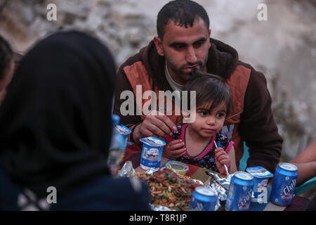 In Gaza. 14 Mai, 2019. Familie Mitglieder der Palästinensischen Mousa Zorub haben ihre Frühstück neben ihren zerstörten Haus im südlichen Gazastreifen Stadt Rafah, am 14. Mai 2019. Das Hilfswerk der Vereinten Nationen für Palästinaflüchtlinge im Nahen Osten (UNRWA) am Montag gesagt, dass mehr als die Hälfte der Bevölkerung im Gazastreifen nicht genug Nahrung bis Juni haben. Quelle: Xinhua/Alamy leben Nachrichten Stockfoto