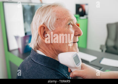 Krankenschwester, die Temperatur ist ein älterer Patient mit einem digitalen Thermometer. Stockfoto