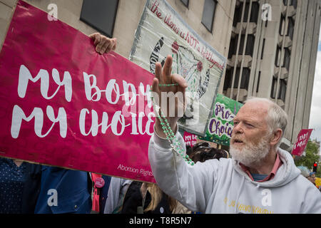 Ein anti-Abtreibung Christian Wellen seinen heiligen Rosenkranz an die Rechte der Frauen pro-choice-Unterstützer wie die Gruppen Zusammentreffen im März für Life UK protestieren. Stockfoto