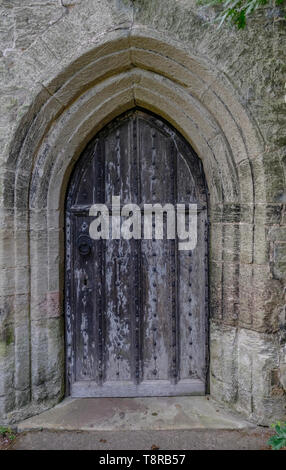 Alte Holztür in einen Stein gesetzt umgeben. Tür hat schöne Black Metal gemusterten Verschluss und verzierte Muster. Zeigt große Textur im alten Holz. Stockfoto