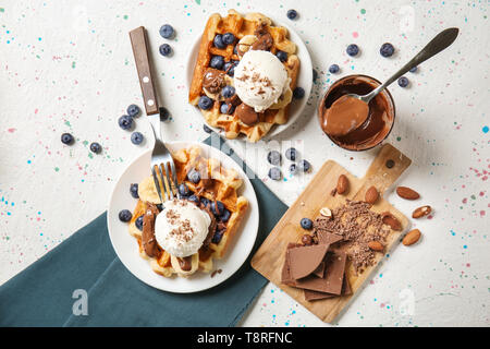 Leckere Waffeln mit Bananenscheiben, Blaubeeren und Eis auf Licht Tabelle Stockfoto
