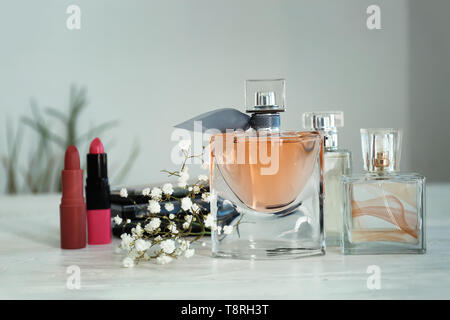 Flaschen Parfüm mit Blumen und Kosmetik auf weißen Tisch Stockfoto