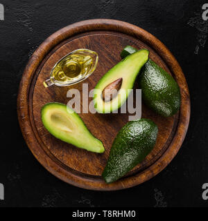 In Scheiben geschnitten und ganze Avocados und Öl an Bord Stockfoto