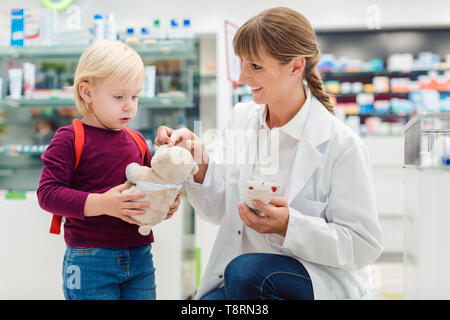 Apotheker Frau mit Kind Kunden und ihre Plüsch Spielzeug in der Pharmazie Stockfoto