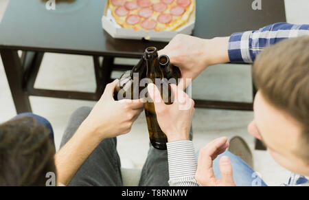 Home Party. Freunde Toasten Bierflaschen, Hohe Betrachtungswinkel Stockfoto