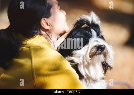 Frau und Hund. Frau mit ihren weißen und schwarzen Tibet Terrier Hund sitzen auf einer Parkbank, in der Nähe Stockfoto