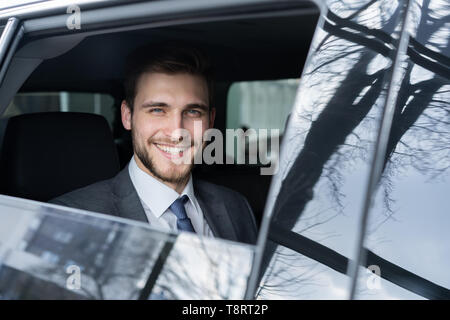 Junge gut aussehender Geschäftsmann sitzt in Luxury Car Stockfoto