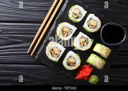 Japanische Rollen aufgewickelt in Avocado mit Omelette, Sesam und Gurke closeup auf einem Teller auf den Tisch. Horizontal oben Ansicht von oben Stockfoto