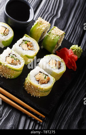 Japanische Brötchen grüner Drache mit Avocado, Omelette tamago, Sesam und Gurke closeup auf einem Teller auf den Tisch. Vertikale Stockfoto