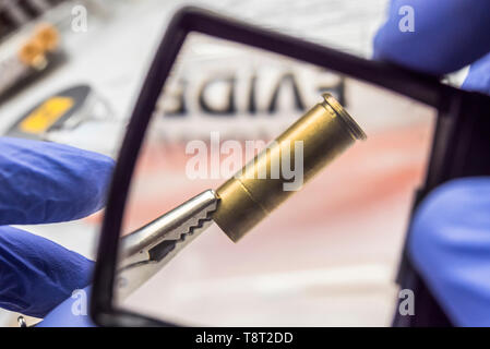 Experten der Polizei untersucht eine bullet Gap im wissenschaftlichen Labor mit Lupe Stockfoto