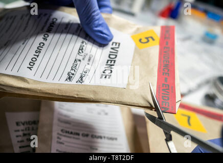 Wissenschaftlichen Polizei öffnet mit der Schere ein Beutel der Beweis eines Verbrechens im wissenschaftlichen Labor Stockfoto