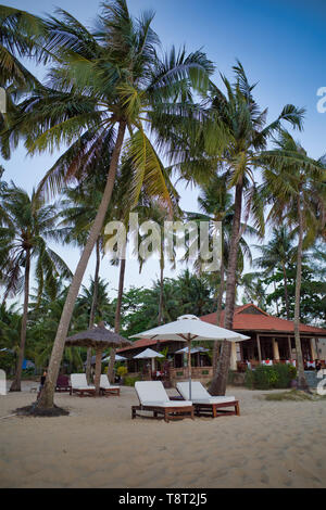 Phu Quoc, Vietnam - März 27, 2019: weiße Liegen mit Sonnenschirm an einem schönen Sandstrand, der von Palmen umgeben Stockfoto