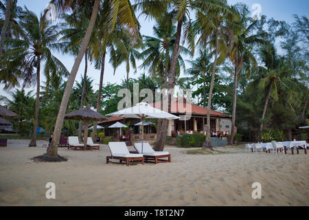 Phu Quoc, Vietnam - März 27, 2019: weiße Liegen mit Sonnenschirm an einem schönen Sandstrand, der von Palmen umgeben Stockfoto