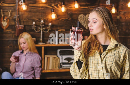 Freunde auf entspannte Gesichter in plaid Kleidung entspannend, defokussiert. Freunde genießen Glühwein in warmen Atmosphäre, Interieur aus Holz. Mädchen entspannende und trinken Glühwein. Rest und Konzept entspannen. Stockfoto