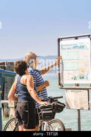 SIRMIONE, Gardasee, Italien - September 2018: Mann und Frau Kontrolle der Fähre Fahrplan am Hafen in Sirmione am Gardasee. Stockfoto