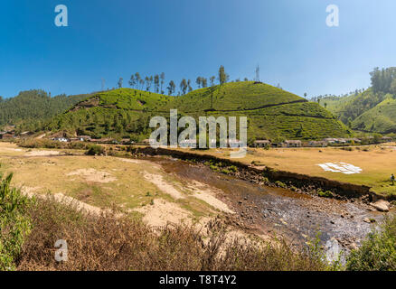 Horizontale Panoramablick auf einer Reihe von hillside Cottages vor einem Fluss in Munnar, Indien. Stockfoto